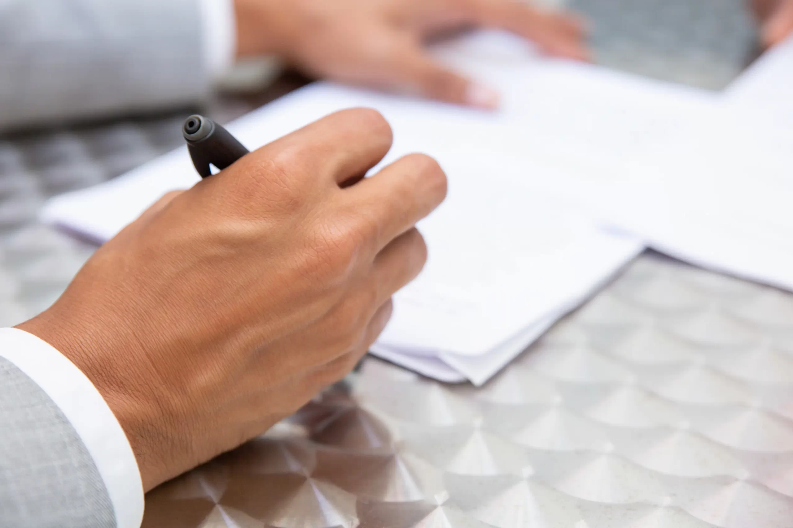 A business professional in a suit holding a pen over blank documents at a meeting table, representing Auditnet Cyprus company registration services.