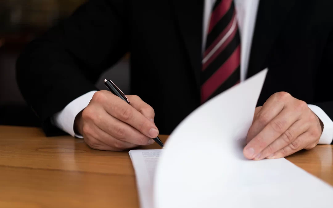 Auditor in a suit signing statutory audit documents at a desk in Cyprus, representing Auditnet's audit and assurance services