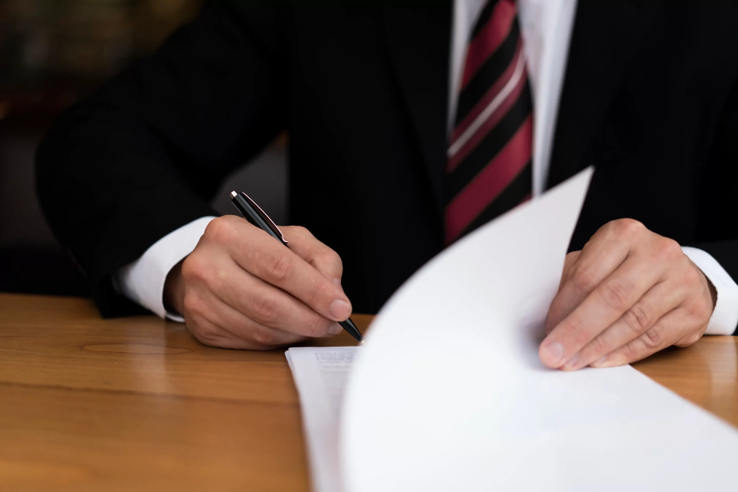 Auditor in a suit signing statutory audit documents at a desk in Cyprus, representing Auditnet's audit and assurance services